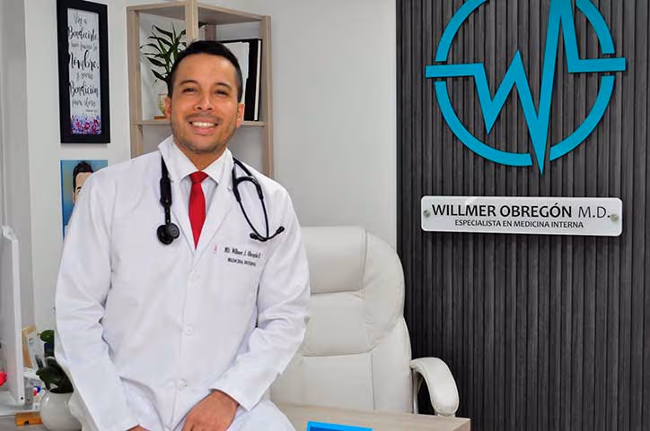 Dr. Willmer Obregón, médico internista en Medellín, sonriendo en su consultorio de medicina interna